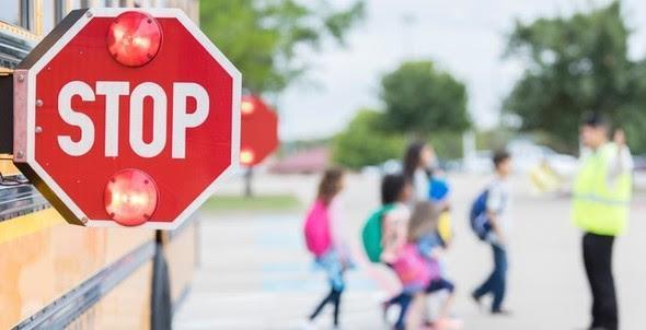 Extended school bus stop sign with students crossing the street